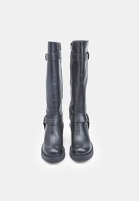 Botas de cuero negras hasta la rodilla con una textura suave, que cuentan con un zipper lateral y dos correas con hebillas en el tobillo y la pantorrilla.