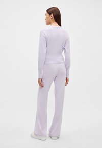 Σετ δύο τεμαχίων σε λιλά απόχρωση που περιλαμβάνει εφαρμοστό μακρυμάνικο τοπ και παντελόνι καμπάνα, κατασκευασμένα από απαλό, υφασμάτινο ύφασμα με ραβδώσεις.