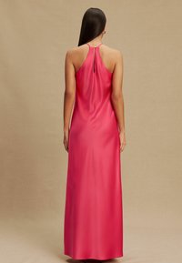 Hosszú rózsaszín szatén ruha, pántos nyakrésszel és kulcslyuk alakú hátkialakítással, sima textúrával és áramló sziluettel.