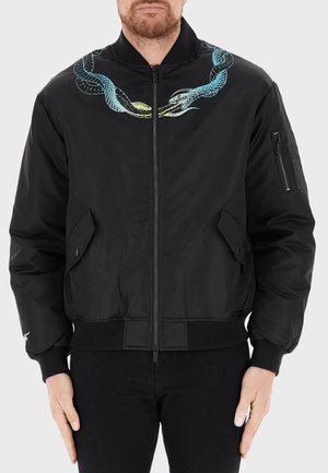 Giacca bomber nera con un design di serpente blu e verde sul petto, polsini a coste, tasche laterali e una zip anteriore.