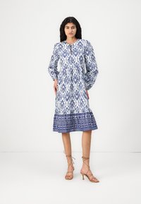 Rochie cu model alb și albastru, cu mâneci lungi, gât rotund și tiv evazat, prezentând modele intricate și o margine decorativă la bază.
