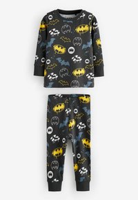 Svart pyjamasset med långa ärmar och byxor som har olika tryckta Batman-logotyper i gult, vitt och blått mot en mörk bakgrund.
