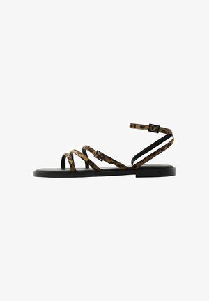Strappy flat sandals with a black sole, featuring leopard print straps and buckle closures. Lightweight design with minimalistic silhouette.