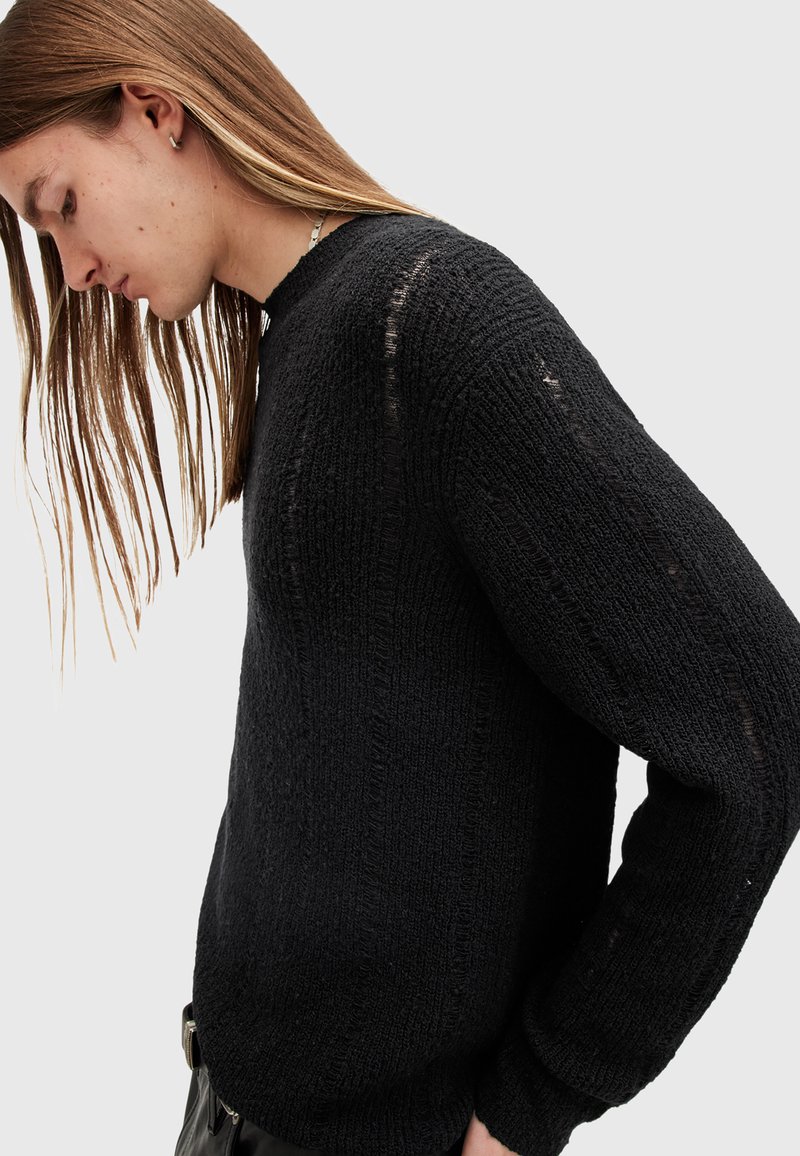 Schwarzer Strickpullover mit gerippter Textur, Rundhalsausschnitt und langen Ärmeln. Besitzt eine lockere Passform und sichtbare Nähte.