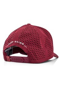 Red perforated cap featuring "KEEP GOING" embroidered in white on the back. Adjustable plastic strap closure at the rear.