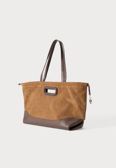 Καφέ τσάντα tote από σουέντ με σκούρες καφέ δερμάτινες λεπτομέρειες, διακοσμημένη με ορθογώνια λαβή με κοπή και κλείσιμο με φερμουάρ, προσφέροντας υφή με αίσθηση.