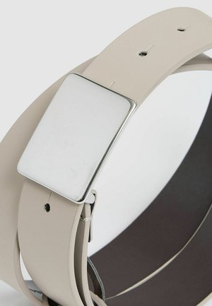 Curea subțire din piele bej, cu o cataramă dreptangulară din argint, având o suprafață netedă și un design minimalist, asigurată printr-un clește metalic.