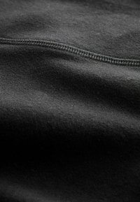 Zwarte stof met een zachte textuur, met een subtiele glans. Zichtbare, fijne stitching langs de rand voegt detail toe.