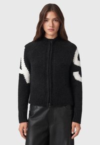 Cardigan zip-up nero con una finitura testurizzata. Presenta un motivo astratto bianco sulle maniche e polsini e orlo a coste. Materiale morbido.