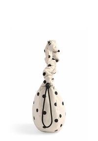 Punktum taske i en flødefarvet stof med sorte prikker, en snøretop og en snorelukning for sikker opbevaring. Rund form.