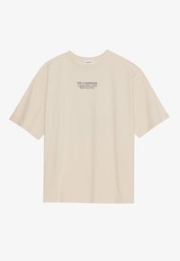 Beige bomulls t-skjorte med korte ermer og rund hals, med "YELLOWSTONE" grafikk i lilla og blått sentrert på brystet.