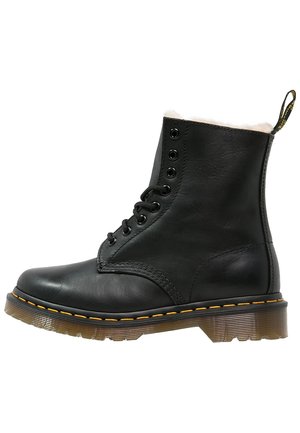 Musta nahkainen nilkkaboots pehmeällä valkoisella vuorilla, pyöreällä kärjellä, kuudella silmukkareijällä, keltaisella ompeleella ja läpinäkyvällä kumipohjalla.