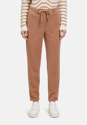 Brune kordfløjs joggers med snoretræk i taljen, tapered fit og opkrøllede manchetter. Sørg for kontrast med hvide sneakers.