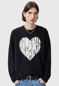 Sort ullgenser som har et stort hvitt hjerte med "AllSaints"-tekst i et stripet mønster. Ribbestrikkede mansjetter og rund halslinning.