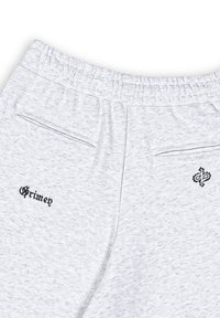Light gray sweatpants with a textured fabric, featuring a black embroidered logo on the left and a decorative accent on the right.