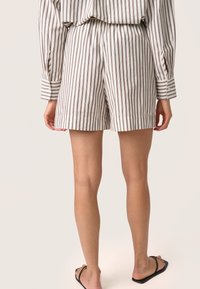 Stribede shorts i hvidt og brunt stof med en afslappet pasform, elastisk talje og opsmøgte kanter, parret med en matchende stribet top.