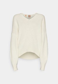 Pull en maille couleur crème avec col en V, longues manches ballon et un ourlet légèrement incurvé, présenté sur un fond gris clair uni.