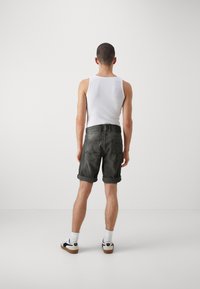 Șorturi din denim gri închis cu margini răsucite, purtate cu un top alb fără mâneci. Au buzunare la spate și un design elegant la talie. Tenisi albi completează ținuta.
