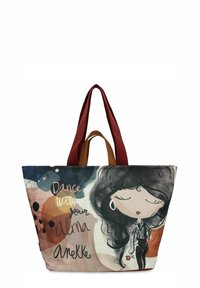 Borsa a tracolla grande con un design colorato che presenta un'illustrazione di una donna. Realizzata in tessuto, ha cinturini rossi e marroni e la scritta "Dance with your Alma."