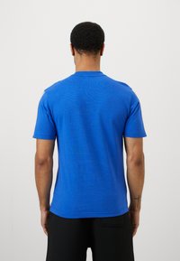 Zils T-krekls ar īsām piedurknēm, izgatavots no kokvilnas, ar apaļu kakla izgriezumu un gludu tekstūru. Nav redzami raksti; vienkāršs dizains ar taisnu piegriezumu.