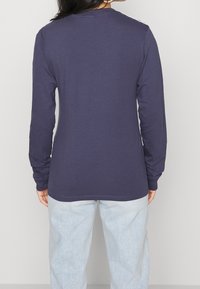 Dlouhý rukáv, námořnickomodré bavlněné tričko s kulatým výstřihem a rovný lem. Má hladkou strukturu a přiléhavé rukávy.