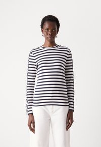 Camicia a maniche lunghe a righe blu navy e bianche in tessuto morbido, con scollo tondo e bottoni decorativi lungo le cuciture delle maniche.