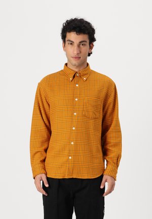 Button-up shirt in orange with a checkered pattern, soft texture, and a chest pocket. Features a pointed collar and white buttons.
