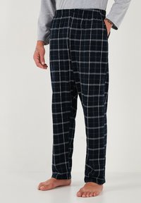 Pantaloni de pijama în carouri navy, cu talie elastică, având linii albe în rețea, două buzunare laterale și o croială lejeră. Material din bumbac.