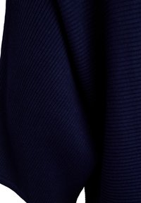 Tmavomodrá pletená látka s rebrovanou textúrou, ktorá ukazuje hlbokú farbu a jemnú konzistenciu, zložená do záhybov na vyjadrenie tvaru a hrúbky.