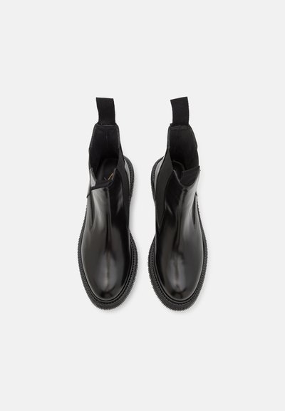 Black leather ankle boots with elastic side panels, round toe, and textured rubber sole. Smooth finish and pull tabs for easy wear.