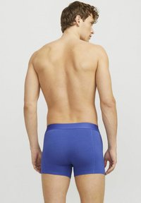 Blue cotton boxer shorts with a smooth texture, featuring a wide waistband. The model is shown from the back, with short, curly hair.