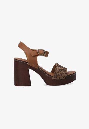 Brown platform sandal with a chunky heel, featuring a leopard print strap and a buckle closure. Stitched accents highlight the design.