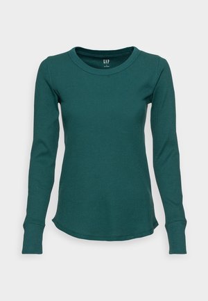 T-shirt à manches longues, col rond côtelé vert foncé avec poignets ajustés et ourlet légèrement arrondi, étiquette GAP à l'intérieur du col.
