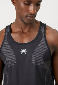 Sort tanktop med strukturerede grå mesh-paneler og et subtilt logo. Fremstillet af et glat materiale, har den et strømlinet design og en tætsiddende form.