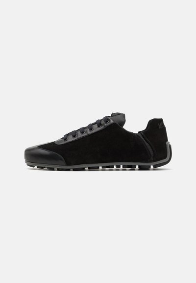 Black athletic shoes with a suede upper, synthetic accents, lace closure, and a textured rubber sole. Features a low profile design.