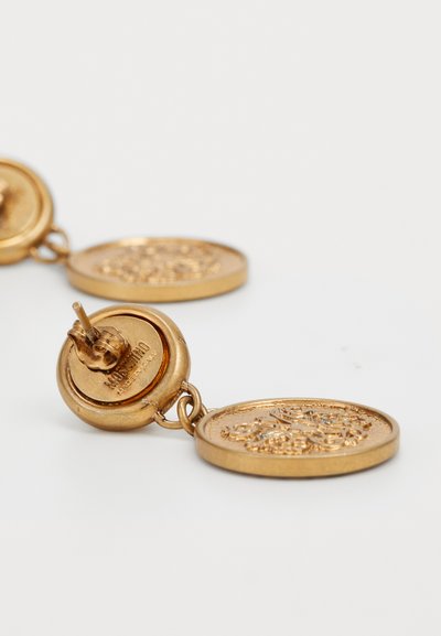Boucles d'oreilles pendantes en ton or, présentant des formes de médaillons ronds avec des motifs embossés complexes et un arrière à clou sécurisé pour la fermeture.