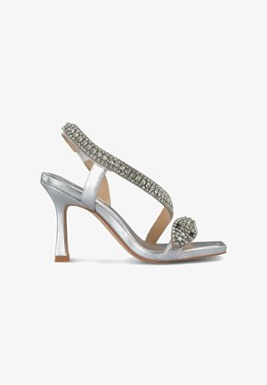Zilveren sandalen met hakken en een glanzende afwerking, met een bewerkte band en versiering op de teen. De hak is ongeveer van gemiddelde hoogte.