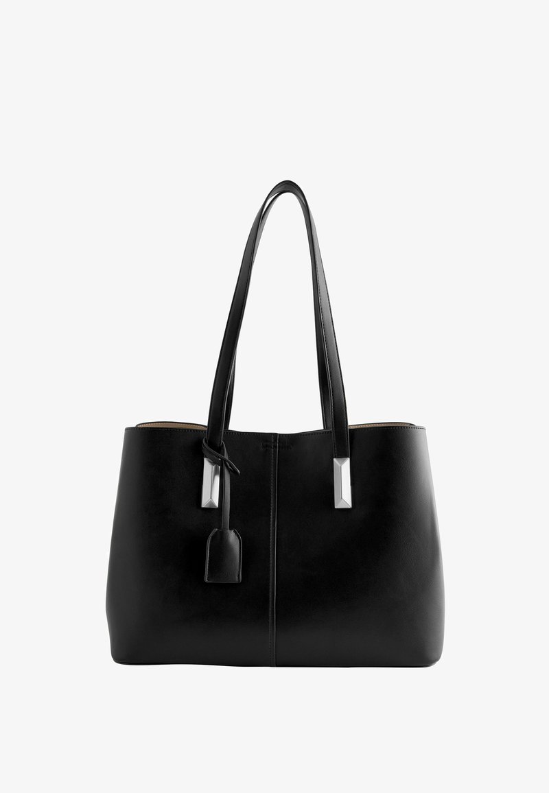 Zwarte leren tote bag met twee lange handvatten, hardwareaccenten in zilverkleur en een afneembare tag. Glad oppervlak en minimalistisch ontwerp.