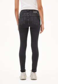 Zwarte spijkerbroek in skinny fit met een hoge taille, twee achterzakken en een logo label aan de bovenkant achter. Aangevuld met lichtgekleurde sneakers.