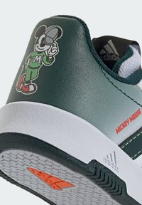 Sneaker verde con tomaia in pelle, caratterizzata da una grafica di Topolino, suola intermedia bianca e accenti arancioni sulla suola. Suola in gomma testurizzata.