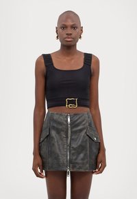 Top corto nero con spalline testurizzate, abbinato a una gonna mini con cerniera frontale e due tasche laterali in pelle grigia distressed.