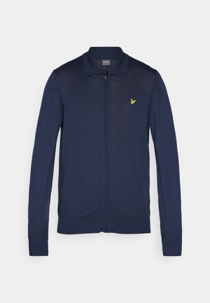 Tengerészkék zipzáras kardigán sima kötött anyagból, klasszikus gallérral és egy kis sárga logóval a bal mellrészen.