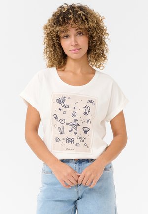 T-shirt crème avec un col rond, des manches courtes et une impression sur le devant présentant des illustrations sur le thème de l'océan en bleu foncé.