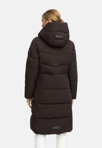 Lång brun puffjacka med huva, med horisontella quiltade sektioner, sidofickor och en logotyp patch på den nedre ryggen.