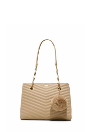 Borsa trapuntata beige con tracolle a catena dorata e un grande portachiavi pom-pom soffice appeso alla tracolla destra.