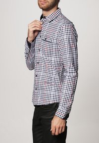 Langarm geruit overhemd in marineblauw, wit en rood. Voorzien van een button-down kraag, borstzak en zwarte knopen. Gemaakt van glad katoen.