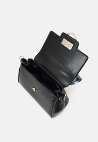 Svart läderhandväska med en slät textur, som har ett guldspänne och två interna fack. Locket är delvis öppet för att avslöja insidan.