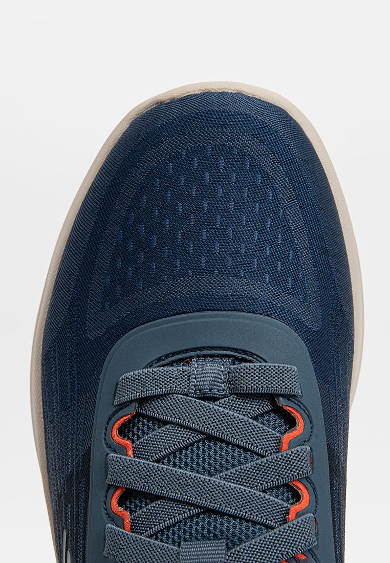 Zapatilla deportiva navy con parte superior de malla texturizada, suela de goma, acentos naranjas y cordones grises. Cuenta con un collar acolchado y una puntera reforzada.