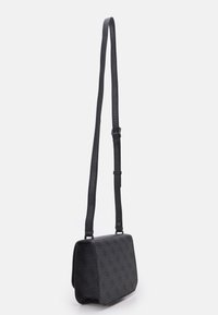 Czarna torba na ramię wykonana z teksturowanego materiału, z klapką na zatrzask, regulowanym paskiem i subtelnym wzorem logo na powierzchni.