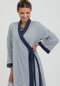 Pasiowana szlafrok w granatowo-białym kolorze, zawiązywany, z szerokimi rękawami i paskiem. Wykonany z miękkiego materiału o teksturowanym wykończeniu.